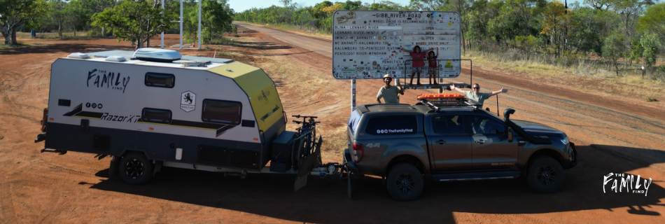 Members of 'The Family Find' standing in front of Gibb River Road conditions sign on Derby side.